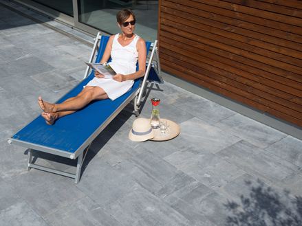 Vrouw ontspant op tuinstoel en blauwe stenen platen Azur