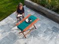 Ontspan in stijl op een Afyon Grijs terras! (klantenproject) Vrouw zittend aan een houten tafel op een terras met marmeren tuintegels