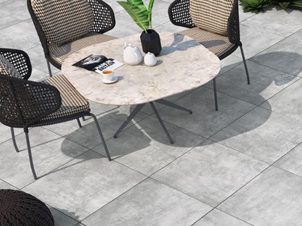 Terras met stoel en fauteuils, vloer van lichtgekleurde keramische tegels met betonlook