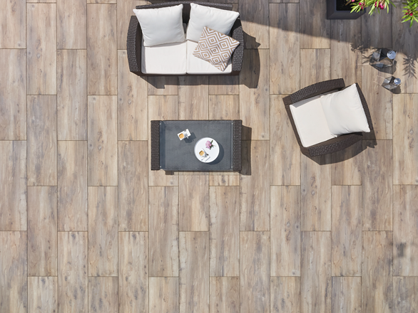 Vogelvlucht van een terras met houtlook platen en modern meubilair