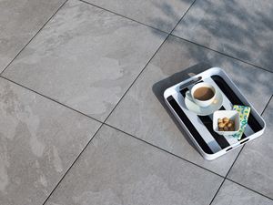 Dienblad met koffie op porcellanato tegels in lichtgrijze Alpine Grey leisteenlook van bovenaf gefotografeerd