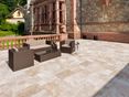 Terrasse mit Gartenmöbeln und Natursteinwand im Hintergrund, Bodenbelag: Travertin Medium mit getrommelter Oberfläche