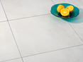 Pure Sand porcellanato tegels in een lichte betonlook met twee decoratieve schalen en een wit plafond