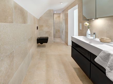Badkamer met moderne meubels en Cleopatra Light kalkstenen tegels op de vloer en muren