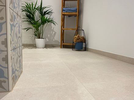 Moderne badkamer met houten meubels, decoratieve plant en lichtgekleurde tegels in kalksteenlook