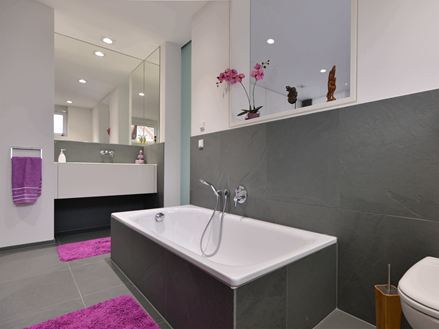 Badkamer met vloer van grijze leisteen, wandbekleding en badkuipbekleding