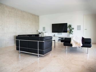 Moderne woonkamer met zwarte banken en lichtbeige Classic Light travertin tegels als vloerbedekking