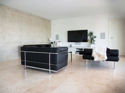 Moderne woonkamer met zwarte banken en lichtbeige Classic Light travertin tegels als vloerbedekking