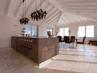 Kookeiland met wijnfleshouder aan het plafond, op de achtergrond eettafel en stoelen op gelegd Travertin Light met getrommeld, niet geÃ«galiseerd oppervlak