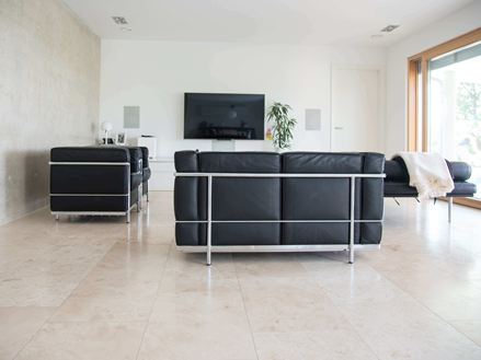 Woonkamer met travertin Classic Light tegels en moderne zwarte bank