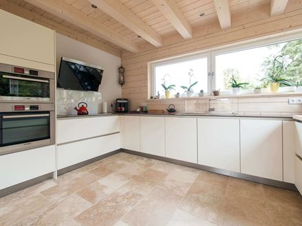 Keuken met witte meubels en beige rustieke travertin tegels als vloerbedekking