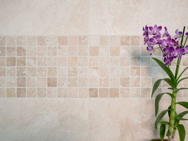 Orchidee voor een mozaÃ¯ekmuur met lichtgekleurd travertin