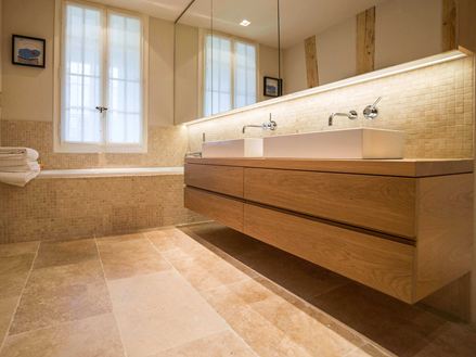 Moderne badkamer met houten wastafel, grote ramen en beige travertin tegels