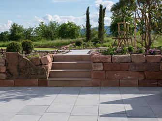 Mediterrane tuin met natuurstenen muur en hardstenen platen van Azur-kalksteen op de voorgrond
