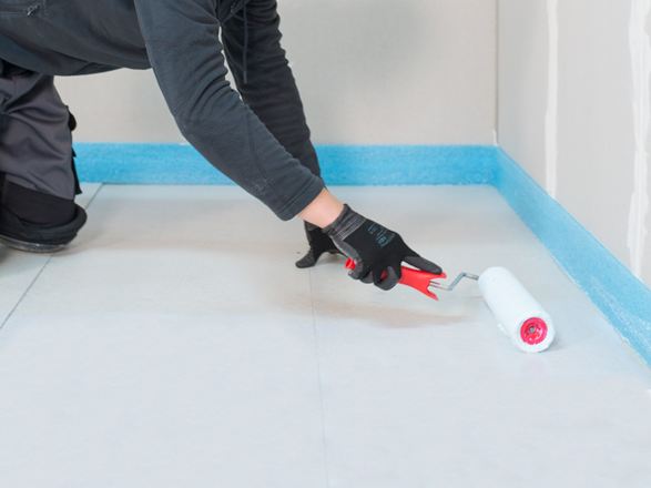 Tegelzetter brengt de primer aan met een roller