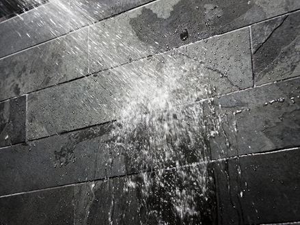 Water op een donkere stenen muur in de badkamer